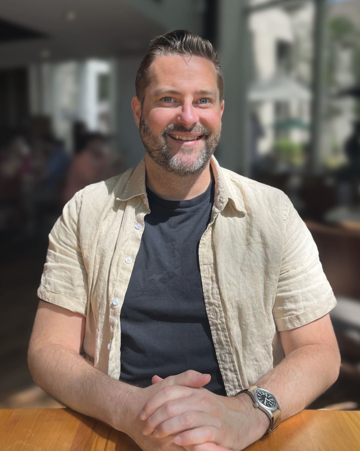 Clark Adriance, founder of Palmetto Pixel, smiling at a table in a sunny Greenville café